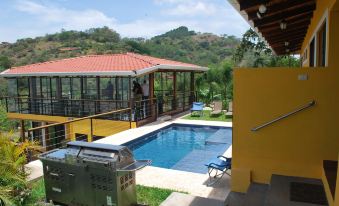 a large swimming pool with a patio and a red roof house in the background at Barons Resort