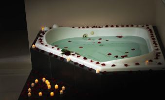 a bathtub filled with water and red rose petals , surrounded by candles and lit by candles at Hotel Mirage