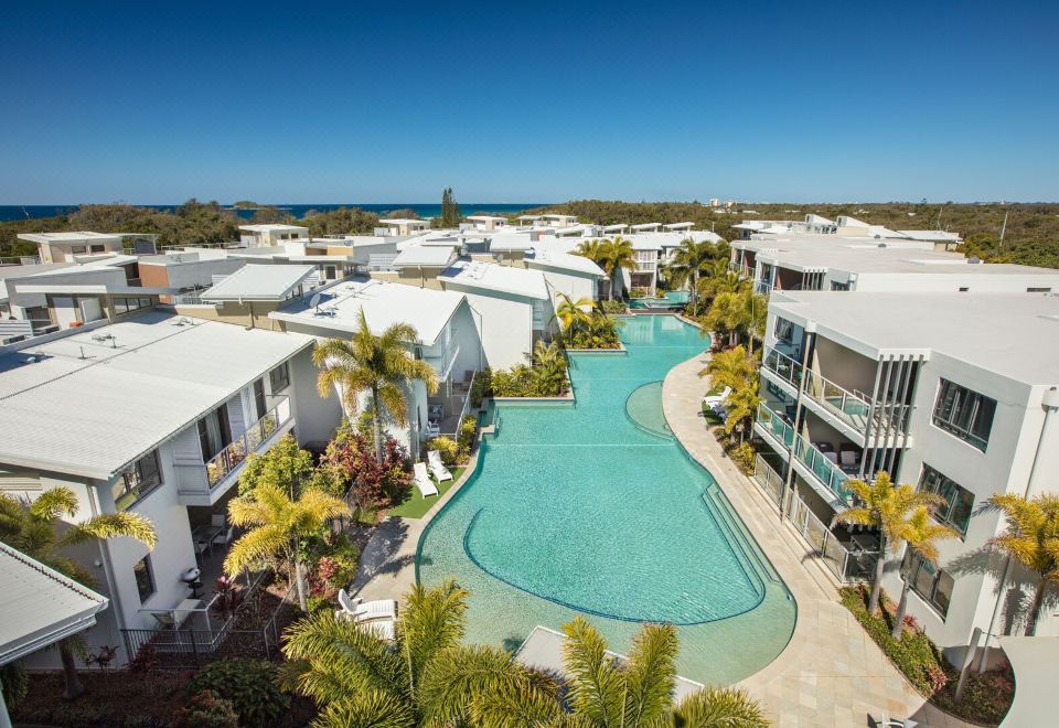 aerial view of a modern apartment complex with a swimming pool , surrounded by palm trees and located near the beach at Sand Dunes Resort