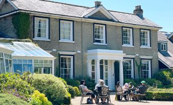 a group of people are sitting outside in front of a large house , enjoying each other 's company at Cbh Park Farm Hotel