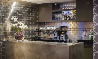 a modern kitchen with a bar counter , wine glasses , and a vase of flowers on the counter at The Hide London