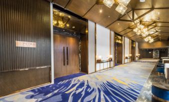 a modern lobby with blue and white carpeting , wooden doors , and a chandelier hanging from the ceiling at Divalux Resort and Spa Bangkok, Suvarnabhumi Airport-Free Shuttle