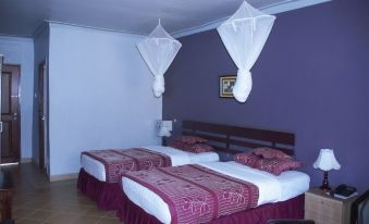 a hotel room with two beds , each having white sheets and red bedspreads , under mosquito nets at Silver Springs Hotel