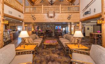 a large , open living room with wooden beams on the ceiling , multiple couches , chairs , and tables at Grand Ely Lodge