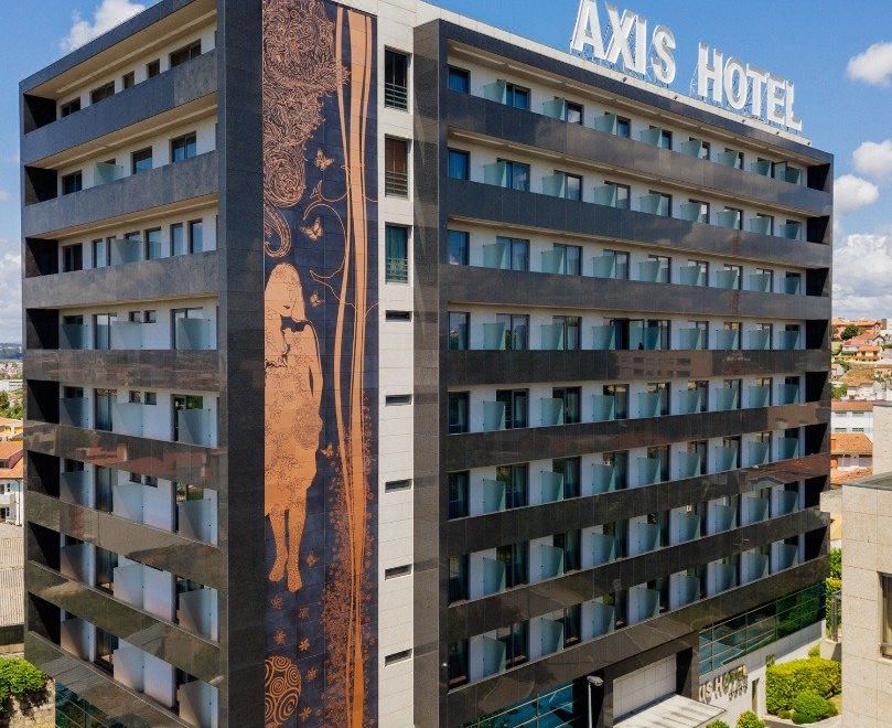 a tall building with a mural on its side , located in a city setting with other buildings in the background at Axis Porto Business & Spa Hotel