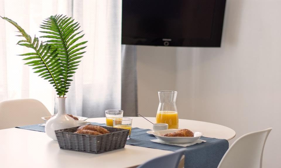 a table is set with a bowl of croissants , a glass of orange juice , and a basket of bread at Beach House