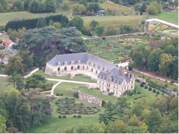an aerial view of a large castle - like structure surrounded by green grass and trees , with a garden in the foreground at Chateau de la Bourdaisiere