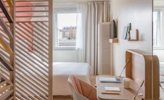 a hotel room with a bed , desk , and chair , as well as a window that allows natural light to enter at Okko Hotels Toulon Centre