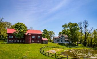 a rural landscape with two red barns surrounded by green grass and trees , located in a grassy field at Inn at Tyler Hill