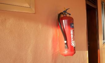 a red fire extinguisher is hanging on a wall in a room , with a window visible in the background at DaysInn Hotel