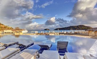 a luxurious beachfront resort with a large pool surrounded by sun loungers , and a cruise ship docked in the background at Royalton Antigua, An Autograph Collection All-Inclusive Resort