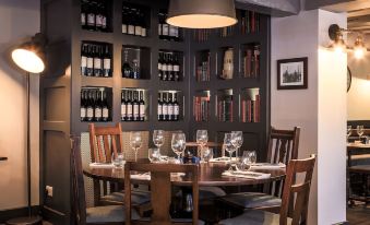 a dining room with a round table surrounded by chairs , and a wine rack behind the table at The Ship Inn
