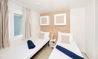 a room with two twin beds , one on the left and one on the right side of the room at Lanterna Premium Camping Resort by Valamar