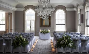 a large , elegant room with rows of chairs arranged in a symmetrical fashion , illuminated by chandeliers and flowers at David Tower Hotel Netanya by Prima Hotels - 16 Plus