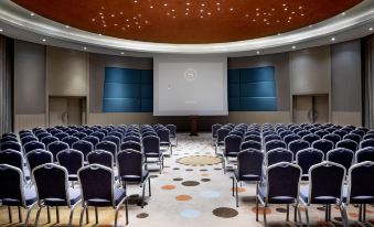 a large conference room with rows of chairs arranged in front of a projector screen at Sheraton Grand Adana