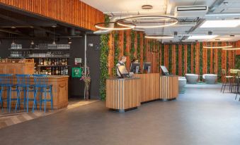 a reception area with a wooden desk and chairs , as well as a man standing behind the desk at Best Western Plus Hotel Amstelveen