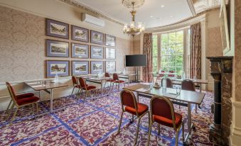 a large , elegant room with multiple tables and chairs arranged for a meeting or event at Reigate Manor Hotel