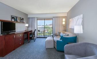 a hotel room with a blue couch , desk , and sliding glass doors leading to a balcony at Courtyard Harlingen