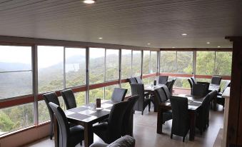 a restaurant with wooden tables and chairs , black leather seats , and large windows overlooking the mountains at Hampton Halfway Hotel Motel