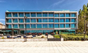 a modern building with multiple floors and large windows , surrounded by potted plants and a seating area at Noa Boutique Hotel