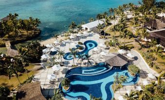 aerial view of a resort with a large pool surrounded by palm trees and beach chairs at Warwick le Lagon Resort & Spa, Vanuatu