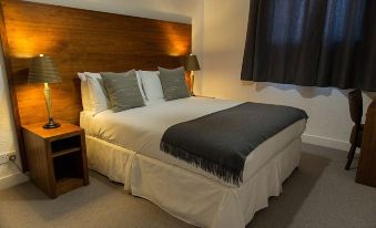 a bed with white sheets and a gray blanket is situated in a room with a wooden headboard at Fife Arms Hotel