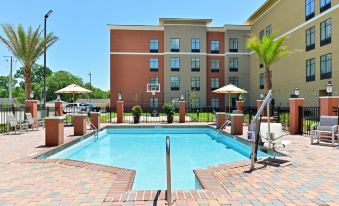 a hotel with a large swimming pool surrounded by multiple umbrellas and chairs , as well as a basketball hoop at Homewood Suites by Hilton Houma