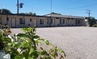 a row of small houses with a gravel driveway and green plants in front at Motel Riverbend