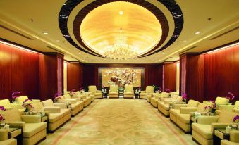 In the middle of a large room with chandeliers, there is a seating area and side tables at JinLing Purple Mountain Hotel Shanghai