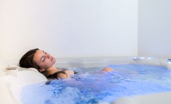 a young woman is relaxing in a bathtub filled with water , enjoying a bubble bath at Hotel Alpino