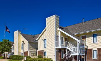 a large apartment building with multiple balconies , surrounded by greenery and a clear blue sky at Sonesta ES Suites Providence - Airport