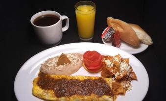 a plate of food with omelette , tomato slices , and toast is displayed next to a glass of orange juice at Plaza Uruapan Hotel