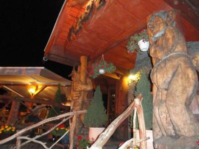 a wooden building with two large statues on either side of the entrance , illuminated at night at Troll
