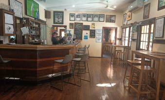 a bar area with wooden floors , a counter with stools , and several framed pictures on the wall at Yanchep Inn