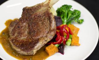 a white plate with a large piece of meat on it , accompanied by various vegetables and a fork at Bonnie Doon Hotel