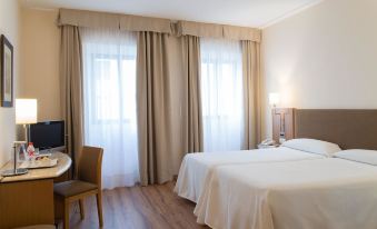 a hotel room with two beds , curtains , and a dining table , all set against wooden flooring at Hotel Inglaterra