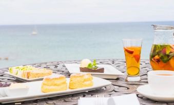 a dining table with a plate of dessert and a glass of iced tea on it at The Bay Hotel