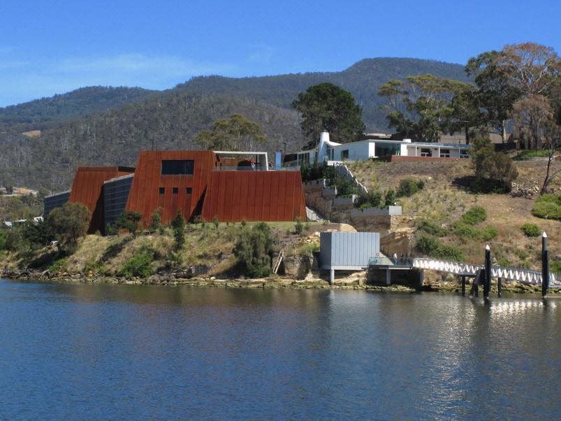a large building with a red roof is situated on a hillside overlooking a body of water at City View Motel