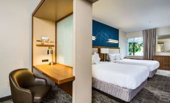 a modern hotel room with a bed , desk , and chair , as well as a view of the outside through large windows at SpringHill Suites Vero Beach