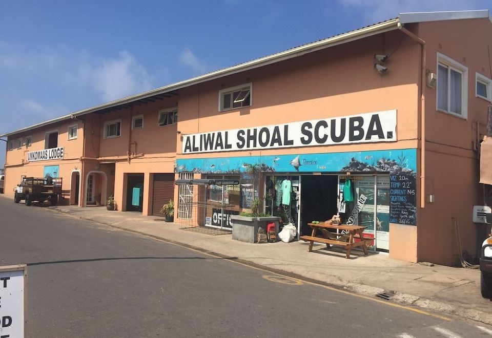 "a building with a sign that reads "" aliwal shoal scuba "" prominently displayed on the front" at Umkomaas Lodge