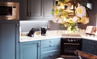 a kitchen with blue cabinets , white countertops , and a hanging light fixture that has flowers on it at Maison