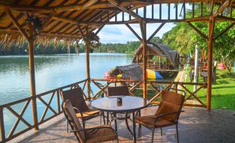 a wooden gazebo overlooking a body of water , with a table and chairs set up for outdoor dining at Shane Josa Resort
