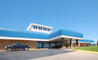 a large building with a blue roof and white columns is surrounded by a parking lot at Best Western State Fair Inn