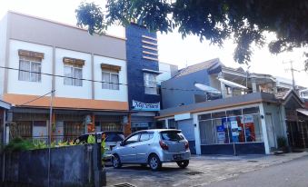 a car is parked in front of a building with an american flag on the side at My Place Guest House Manado