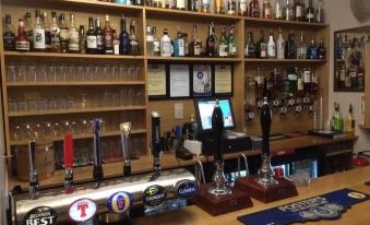 a bar with a variety of beer taps , along with various bottles and glasses on shelves at Loch Shiel Hotel
