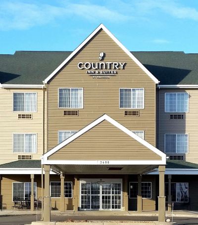 a large hotel building with a brown and beige color scheme , featuring multiple balconies and a covered entrance at Country Inn & Suites by Radisson, Watertown, SD