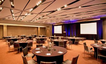 a conference room with round tables and chairs , surrounded by large screens and blue lighting at W Atlanta – Downtown