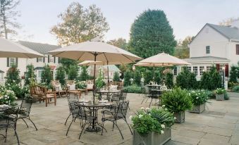 an outdoor dining area with tables , chairs , and umbrellas , providing a pleasant atmosphere for guests to enjoy at The Red Fox Inn & Tavern