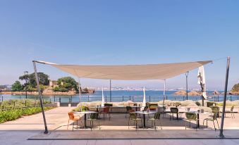 an outdoor dining area overlooking the ocean , with a variety of tables and chairs arranged for guests to enjoy at Noa Boutique Hotel