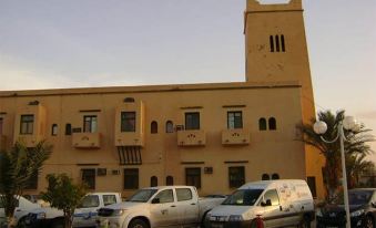 a white van is parked in front of a yellow building with a tall tower at Hotel Antar